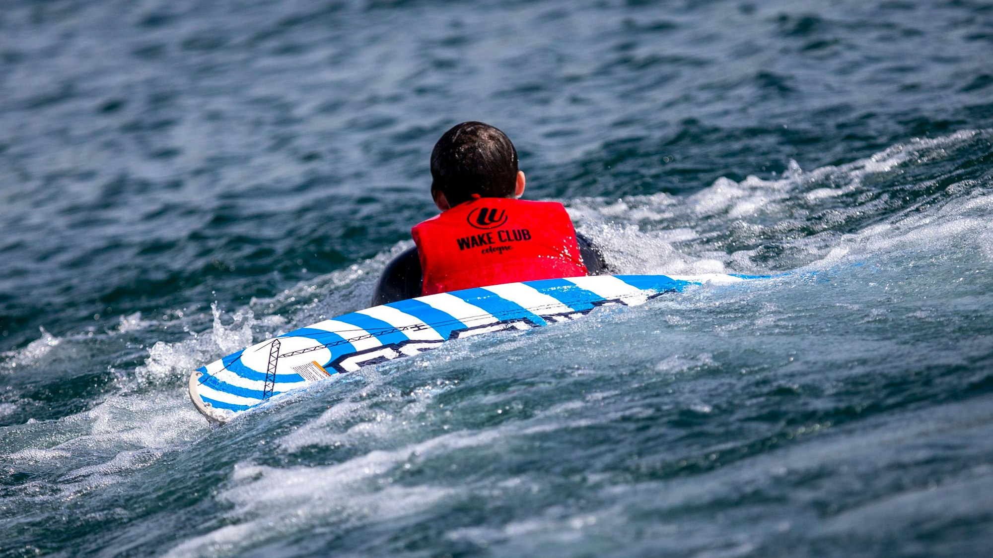 Ein Wakeboarder liegt auf dem Wasser.