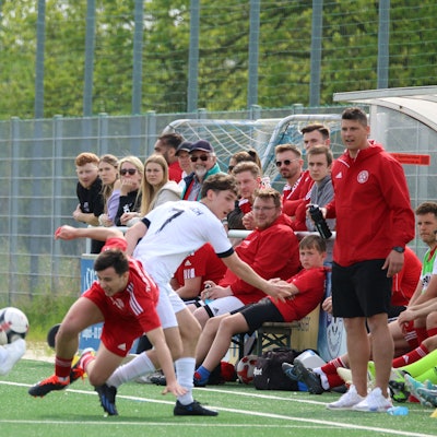 Ein Zülpicher Spieler wird direkt vor der Bank seiner Mannschaft gefoult. Ein weiterer Gegenspieer gelangt so an den Ball.