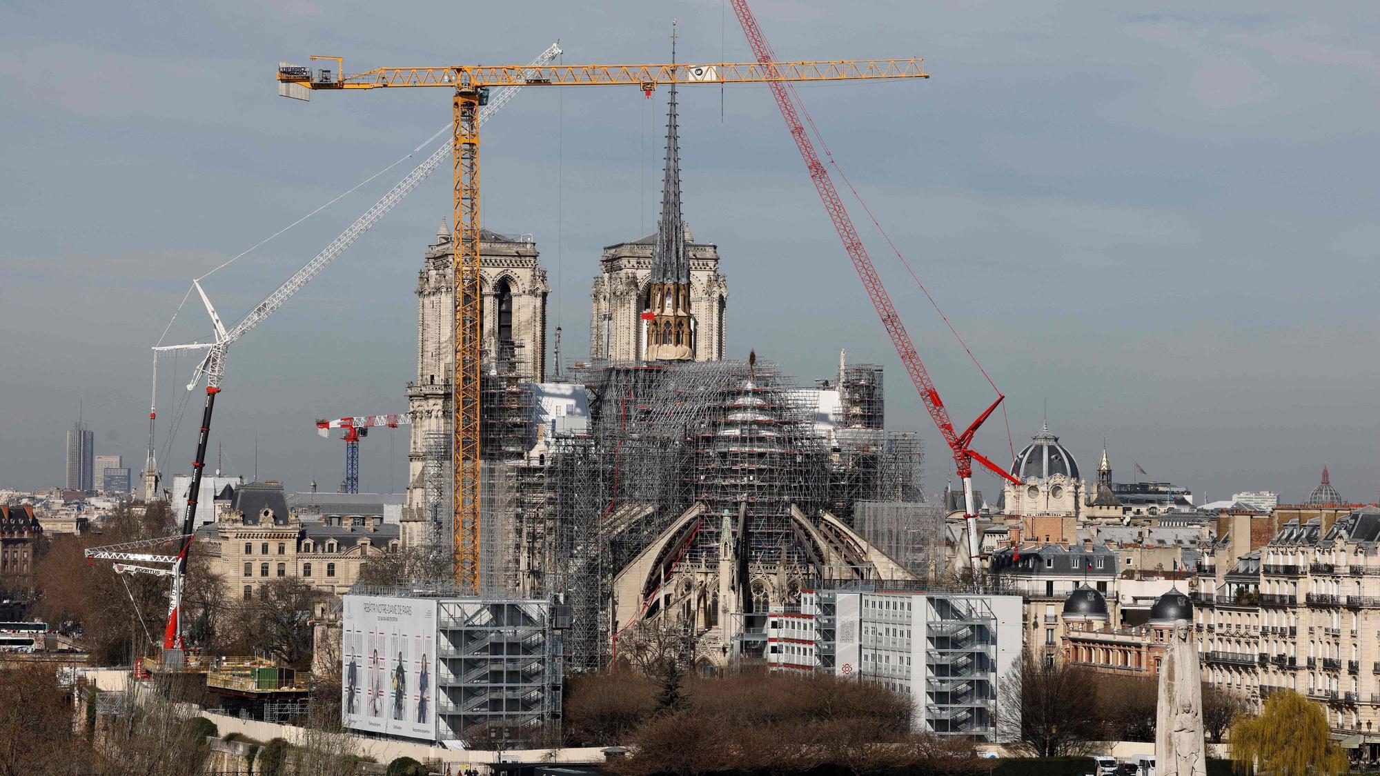(FILES) This photograph taken on March 14, 2024, shows a view of the Notre-Dame de Paris Cathedral and its new wooden spire partially covered in lead under reconstruction with cranes and scaffholdings in Paris. A huge fire swept through the roof of the famed Notre-Dame Cathedral in central Paris on April 15, 2019, and five years later, the reconstruction advances in its final stages before the reopening planned for the end of the year. (Photo by Ludovic MARIN / AFP)