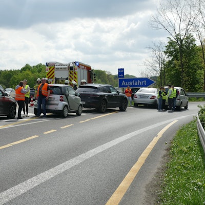 Mehrere Fahrzeuge stehen auf der Fahrspur der Ausfahrt, dazwischen Menschen mit Warnwesten.