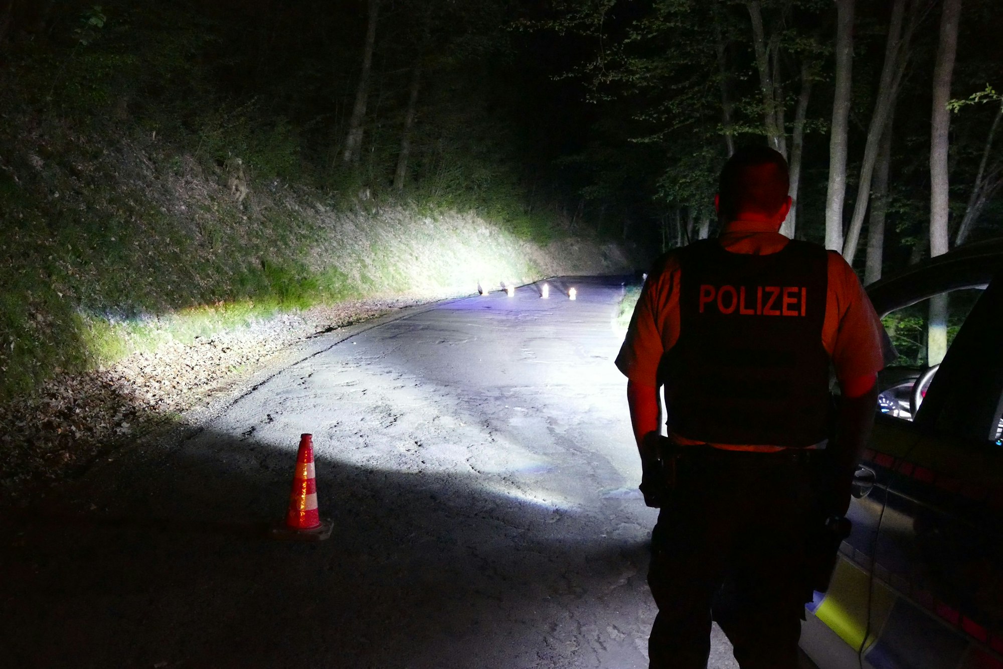 Ein Polizist blickt im Dunkeln auf einen abgesperrten Bereich.