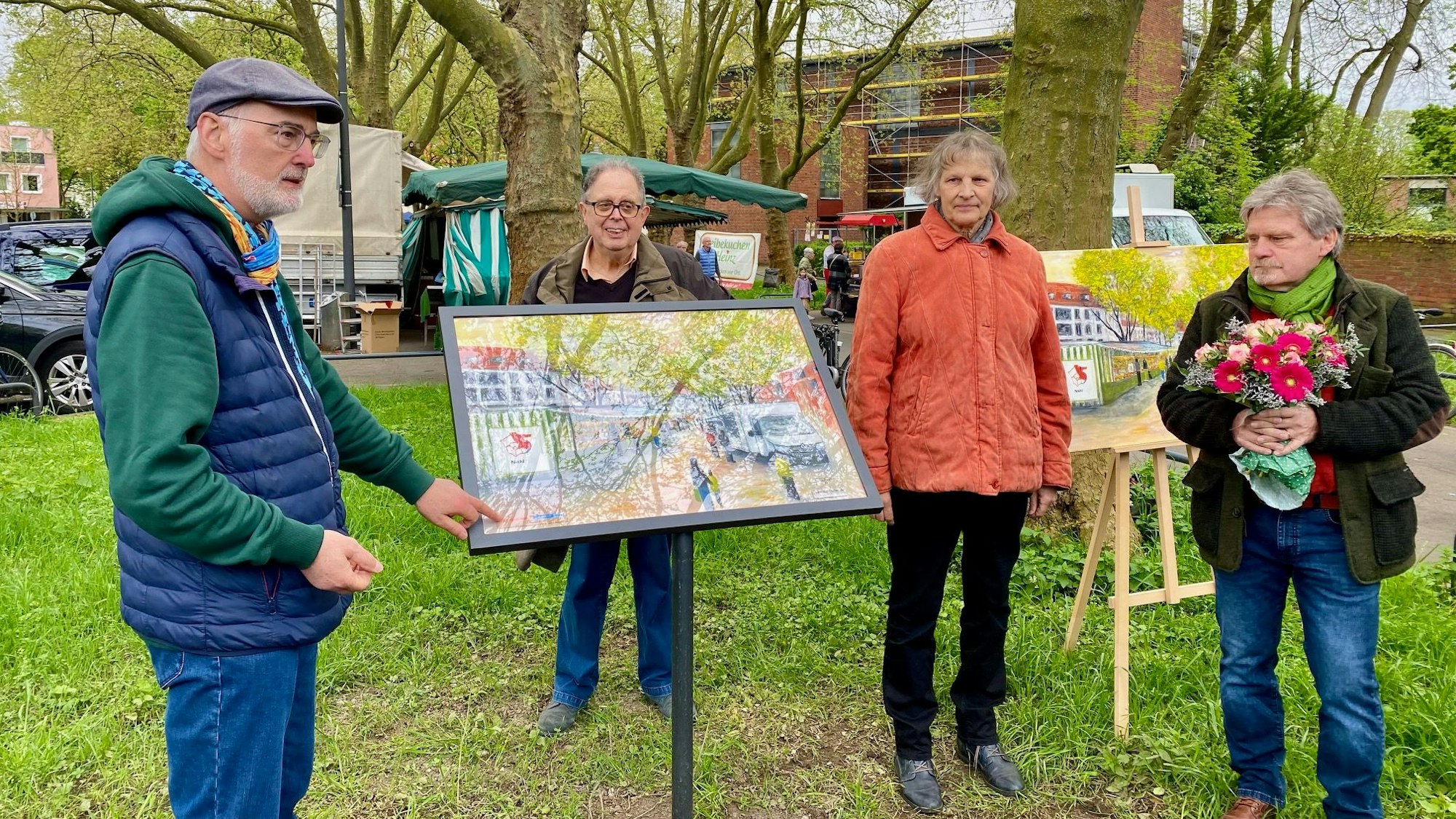 Horst Zedow, Künstler Wolfgang Schieffer, Bezirksbürgermeisterin Diana Siebert und Ulrich Thome (Niehler Bürgerverein) (v.l.) stehen vor dem Kunstwerk für den Niehler Wochenmarkt. Links steht die am Markt ausgestellte Reproduktion, rechts das Original in Ölfarben. Foto von Bernd Schöneck