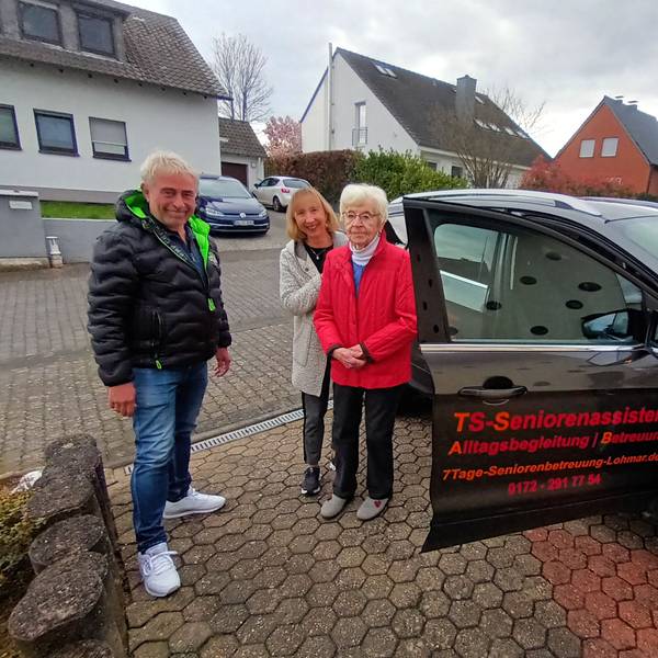Ein Mann und zwei Frauen stehen an einem Auto