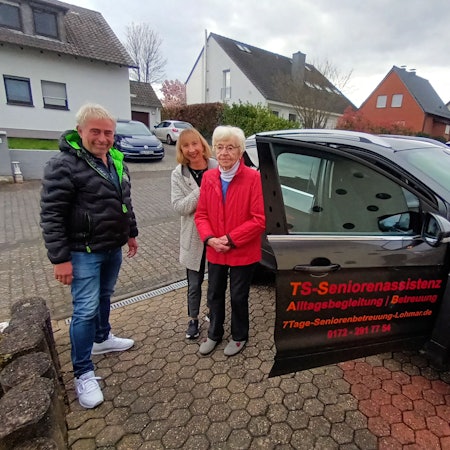 Ein Mann und zwei Frauen stehen an einem Auto