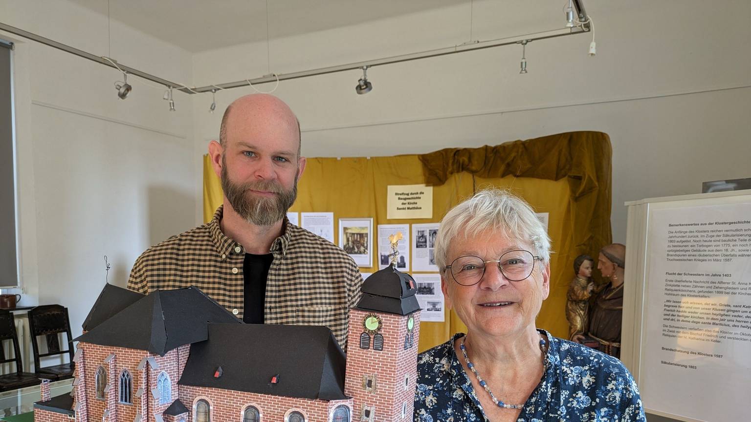 Bärbel Steinkemper und Robin Huth vor dem Modell der Pfarrkirche St. Matthäus im heutigen Zustand.