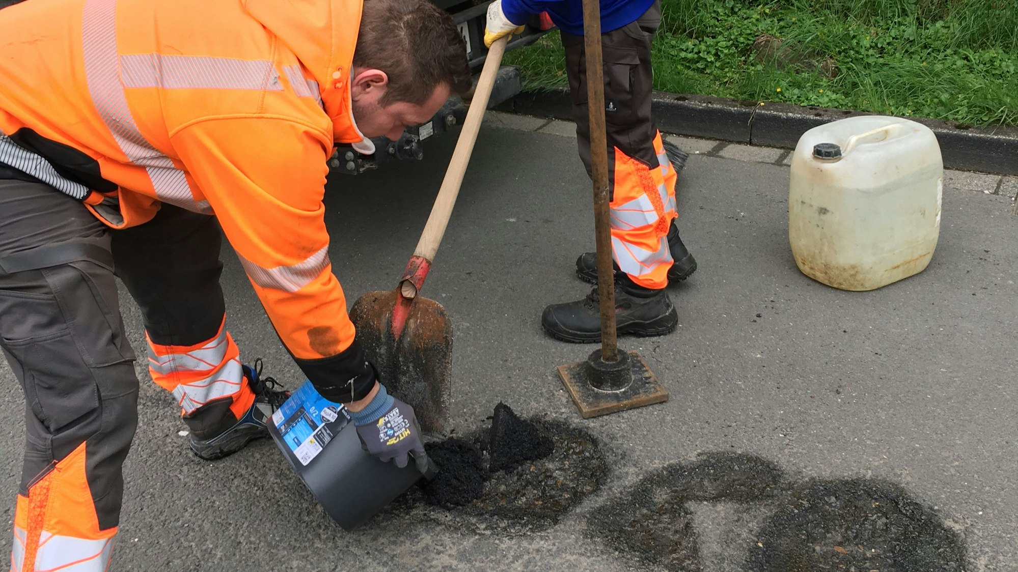 Ein Mitarbeiter des Gummersbacher Baubetriebshofs verfüllt im Stadtteil Berstig ein Schlagloch mit frischem Asphalt.