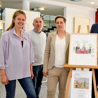 Zwei Männer und drei Frauen haben sich um eine Bild gruppiert.