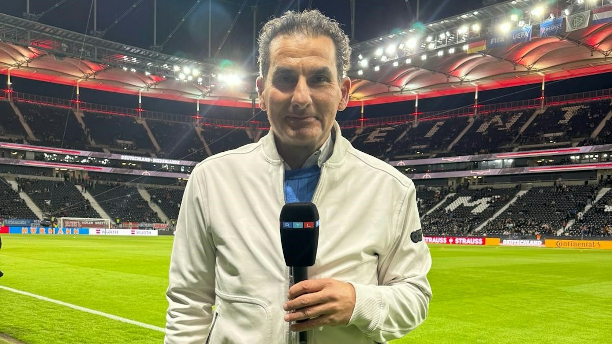 RTL-Sportreporter Felix Görner steht mit einem Mikrofon in einem Stadion.