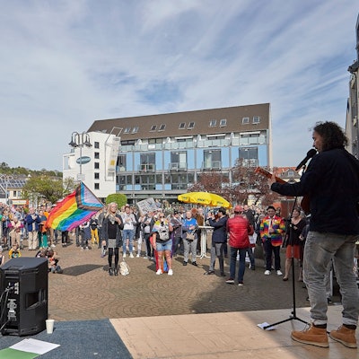 Stephan Brings steht mit der Gitarre auf der Bühne. Das Foto, das von einem Standpunkt hinter der Bühne aus gemacht wurde, zeigt zudem die Teilnehmer der Demo.