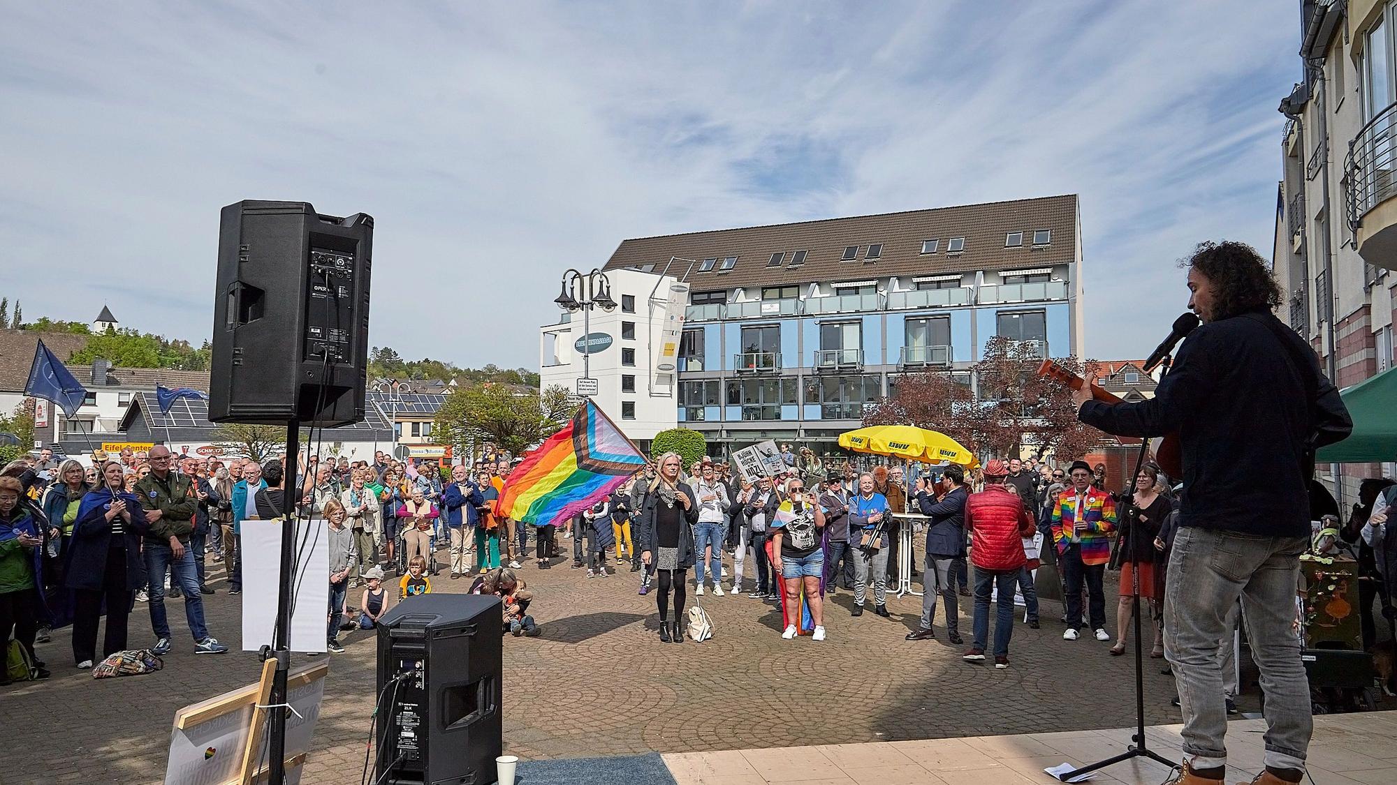 Stephan Brings steht mit der Gitarre auf der Bühne. Das Foto, das von einem Standpunkt hinter der Bühne aus gemacht wurde, zeigt zudem die Teilnehmer der Demo.