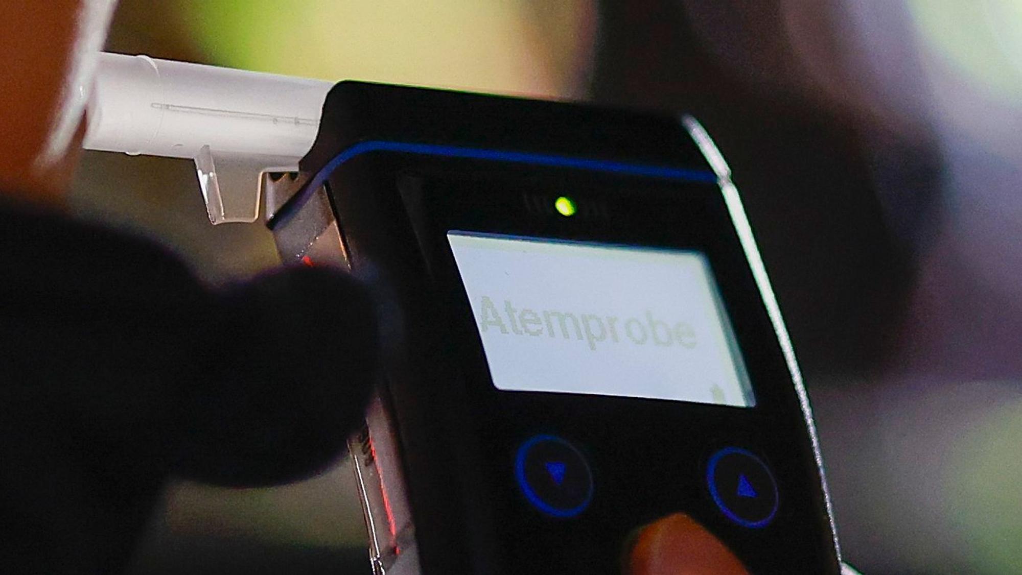 Eine Polizistin misst den Atemalkoholgehalt eines Autofahrers mit einem Alkoholtester. (Symbolbild)