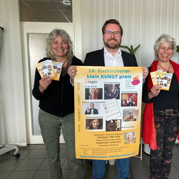 Gaby Bärenklau und Heike Jachtmann halten das Programmheft des 16. Euskirchener Kleinkunstpreises in den Händen. Sie flankieren Sebastian Zimer, der das zugehörige Plakat präsentiert.
