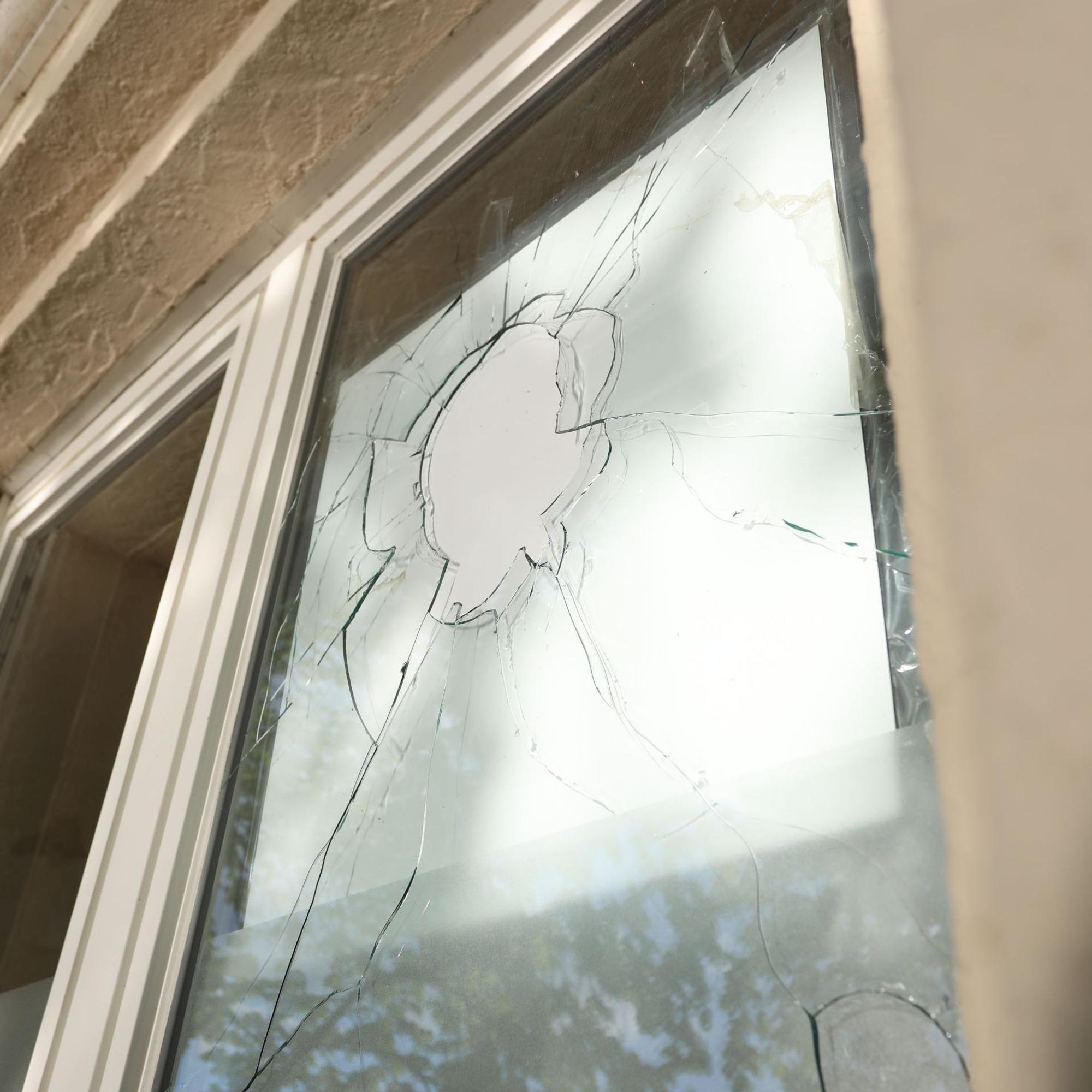 Eine Fensterscheibe mit einem Loch und Rissen.