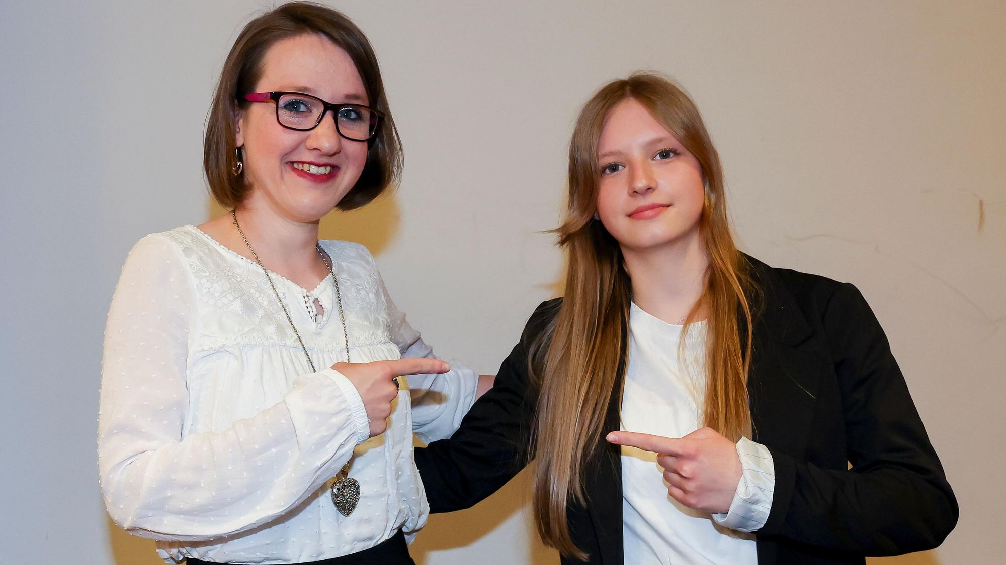 Franziska und Paula Dziallas lächeln und zeigen mit den Fingern auf sich.