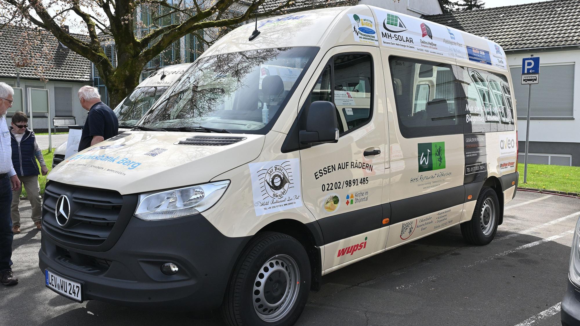 Ein weißer Kleinbus mit Werbebeschriftung steht auf einem Parkplatz.