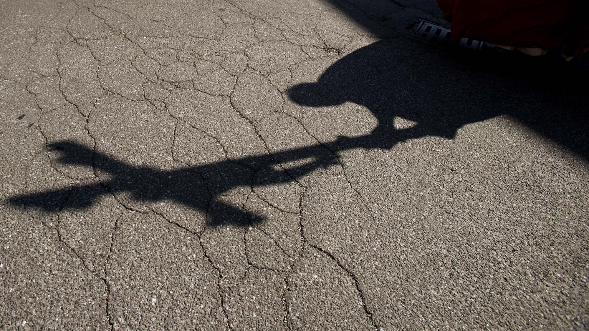 Der Schatten eines Priesters, der bei einer Zeremonie ein Kreuz trägt, fällt auf das Pflaster.