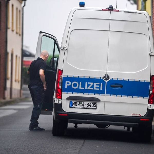 Ein Polizist steht an der geöffneten Fahrertür eines weißen Transporters. Auf einem blauen Streifen steht der Schriftzug „Polizei“.
