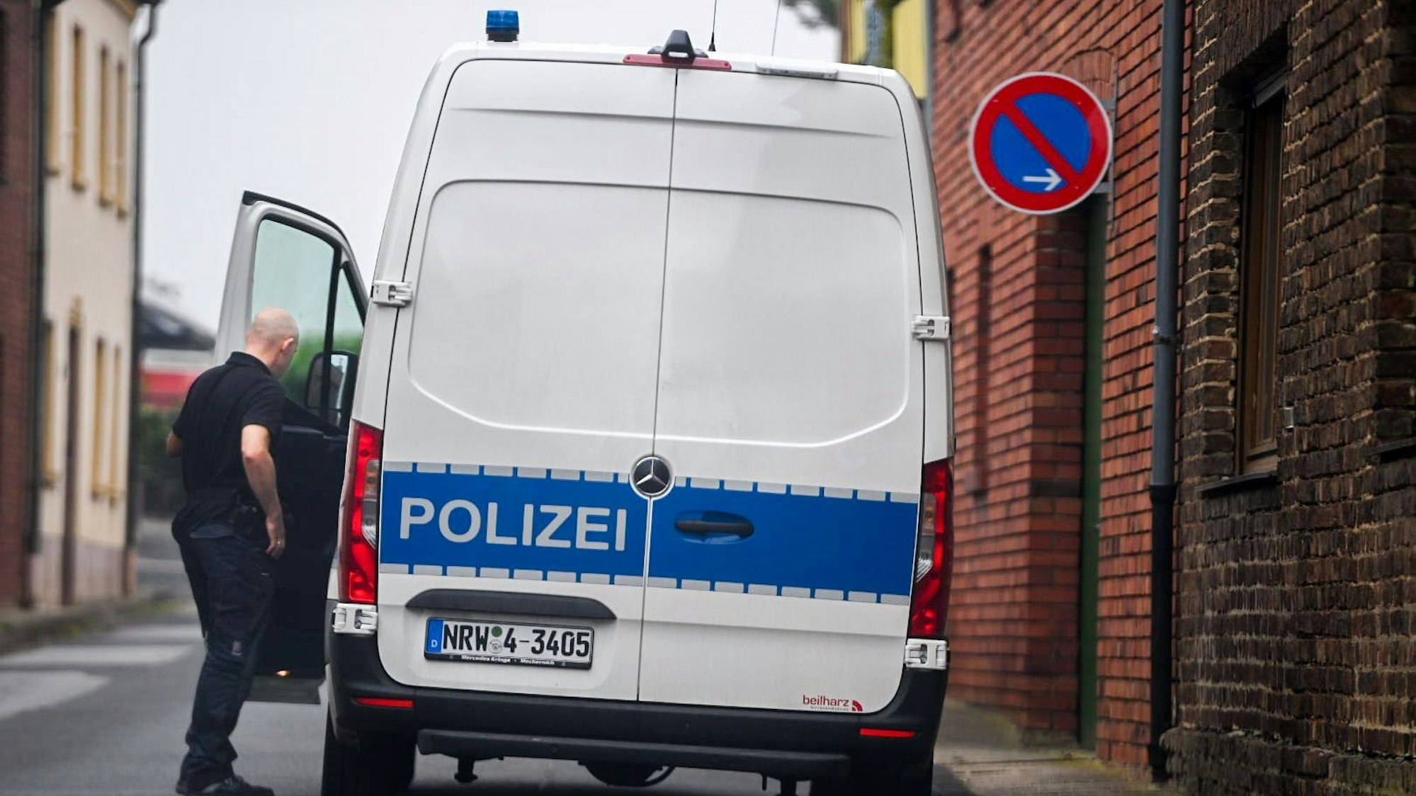 Ein Polizist steht an der geöffneten Fahrertür eines weißen Transporters. Auf einem blauen Streifen steht der Schriftzug „Polizei“.