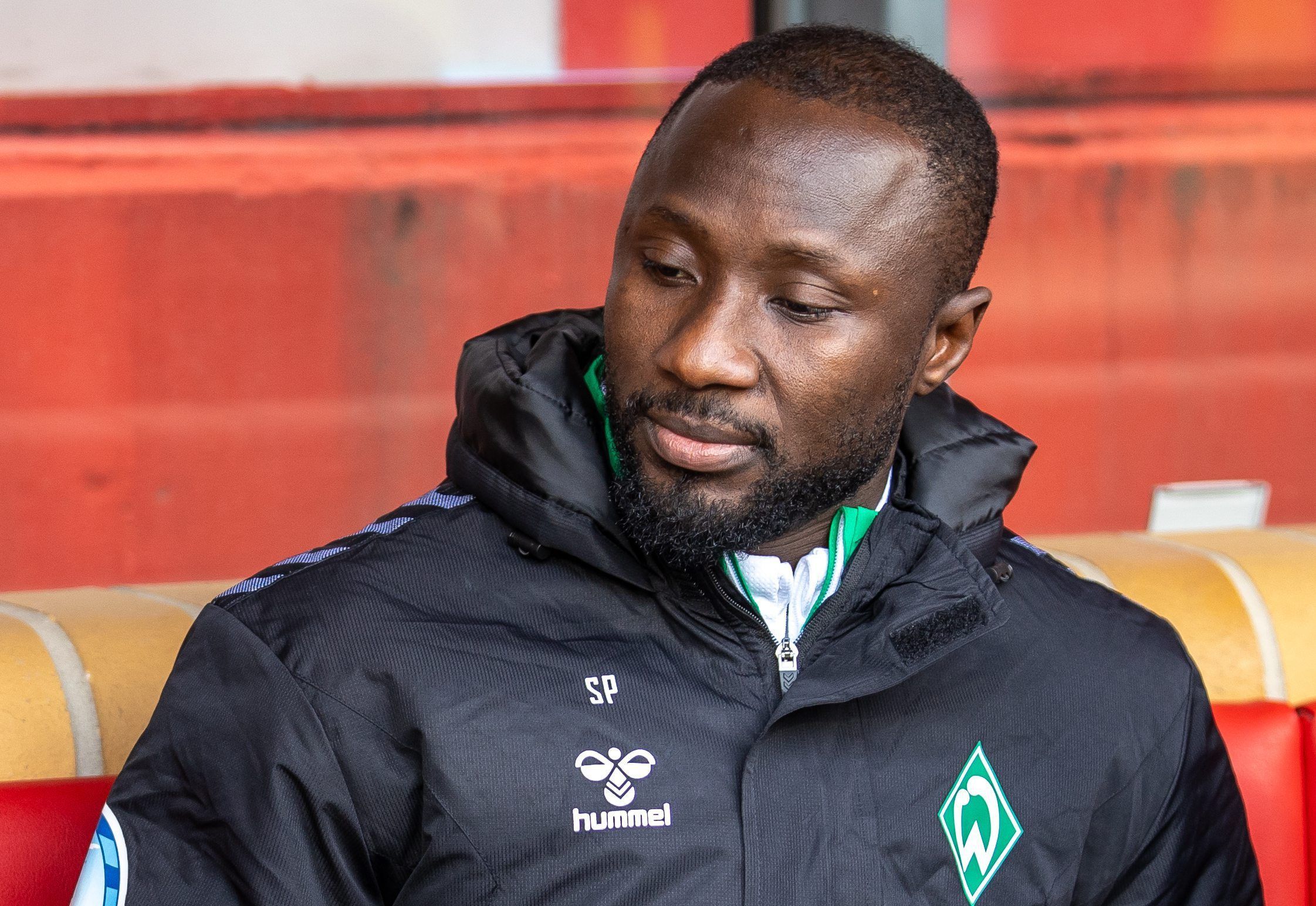 Naby Keita von Werder Bremen sitzt auf der Bank und blickt nach unten.
