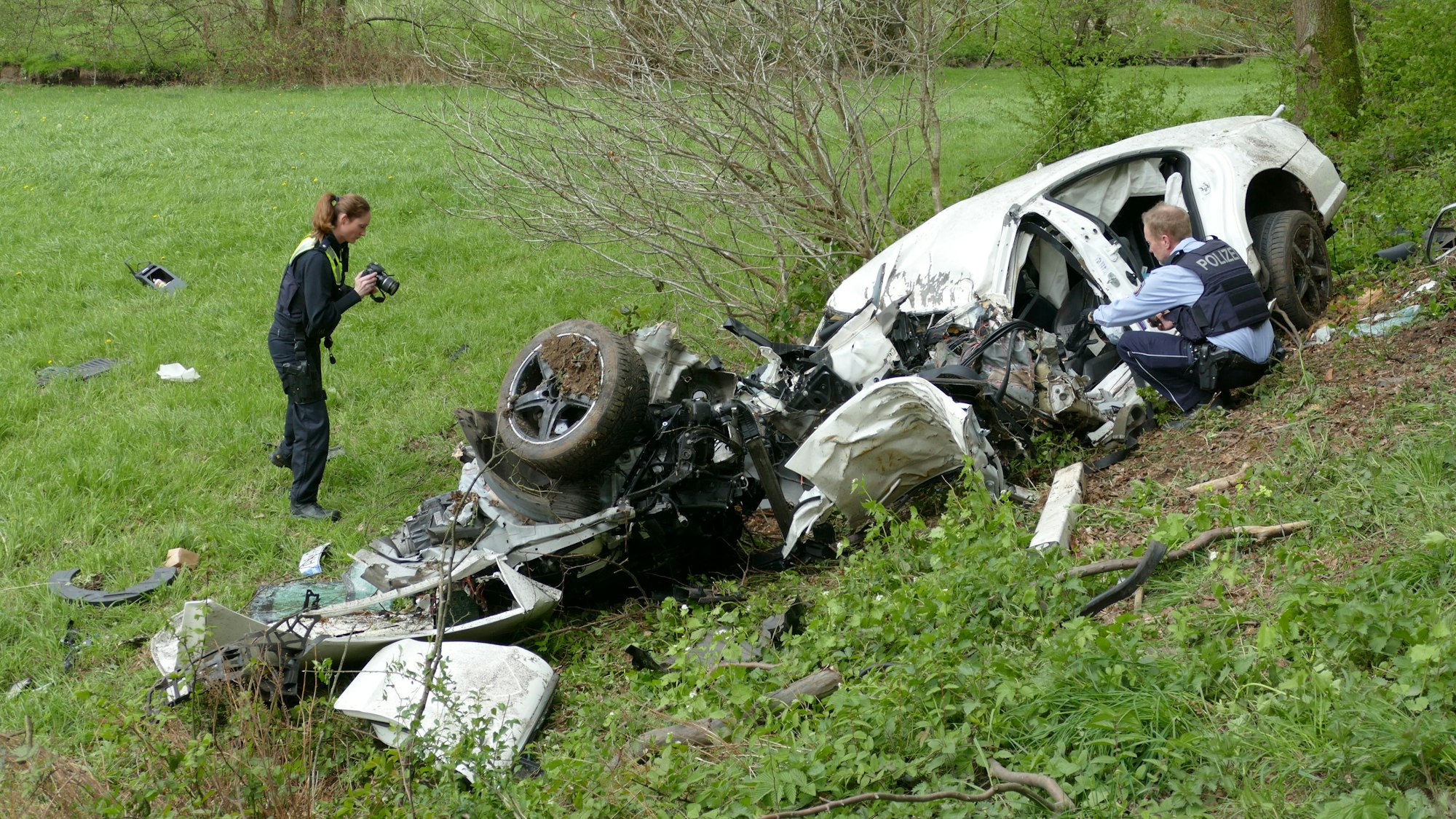 Polizeibeamte untersuchen das Unfallwrack in Much.