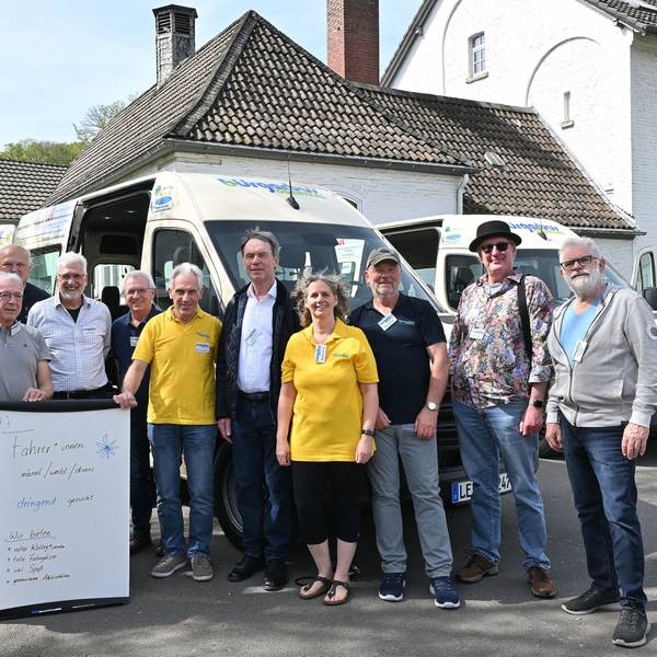 Viele Menschen stehen vor einem Kleinbus.