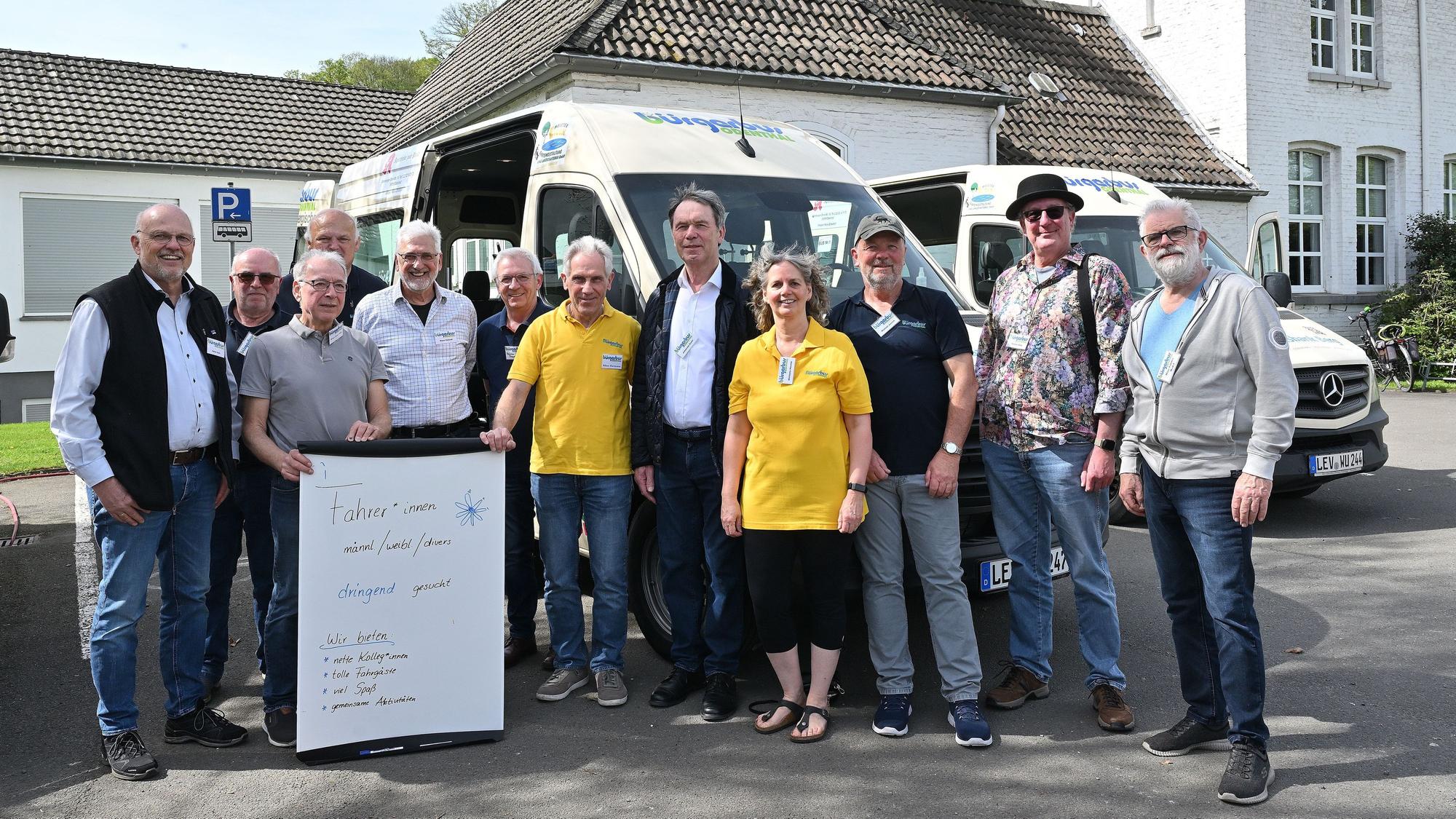 Viele Menschen stehen vor einem Kleinbus.