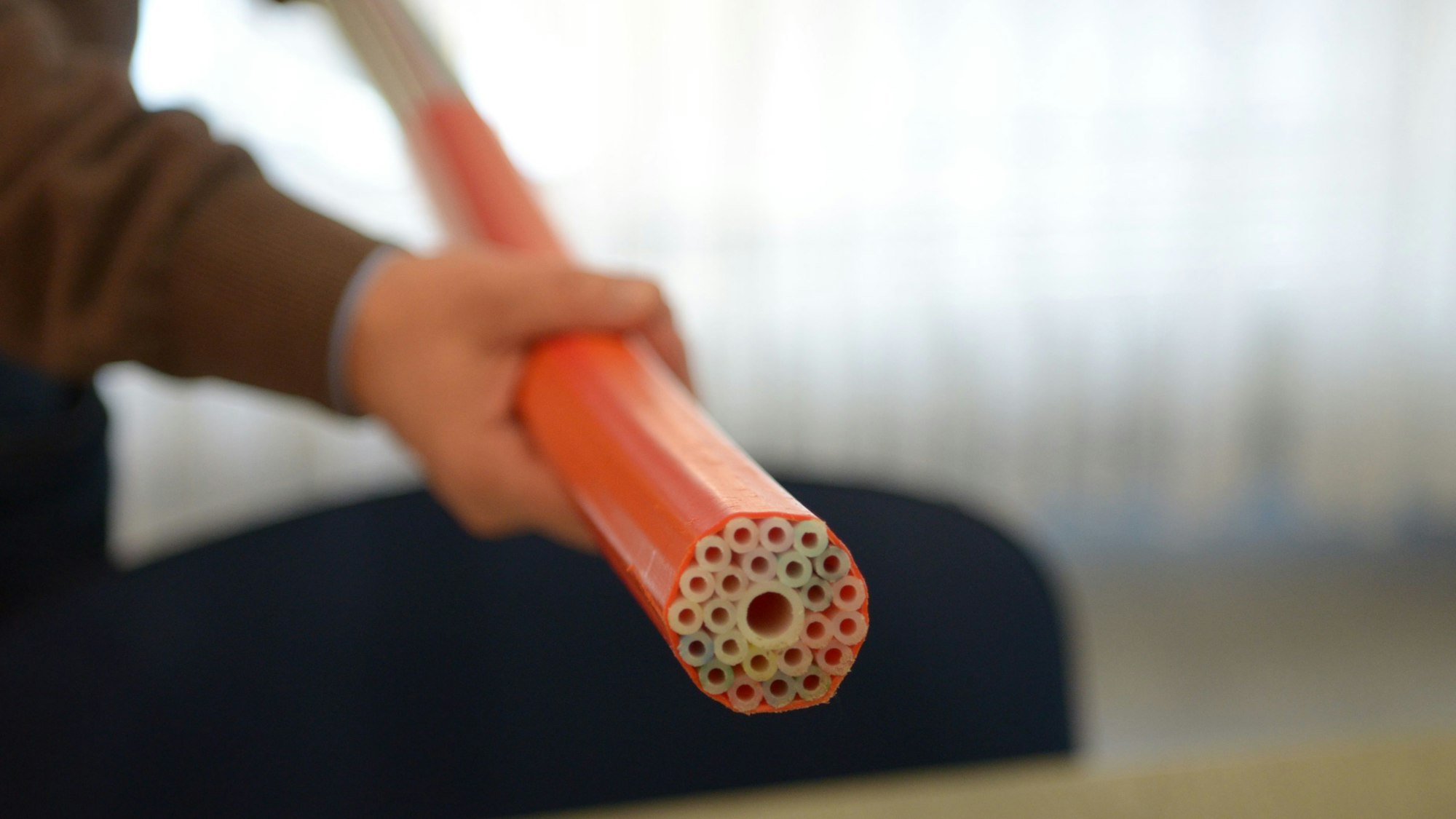 Eine Person hält ein Glasfaserkabel in der Hand.