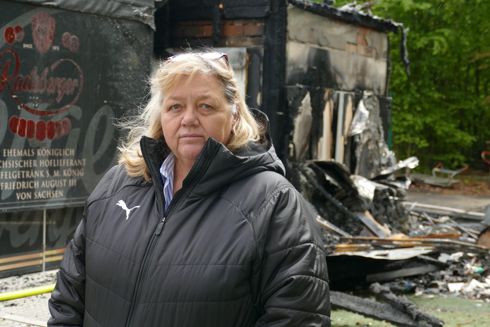 Eine Frau steht vor Brandschutt.