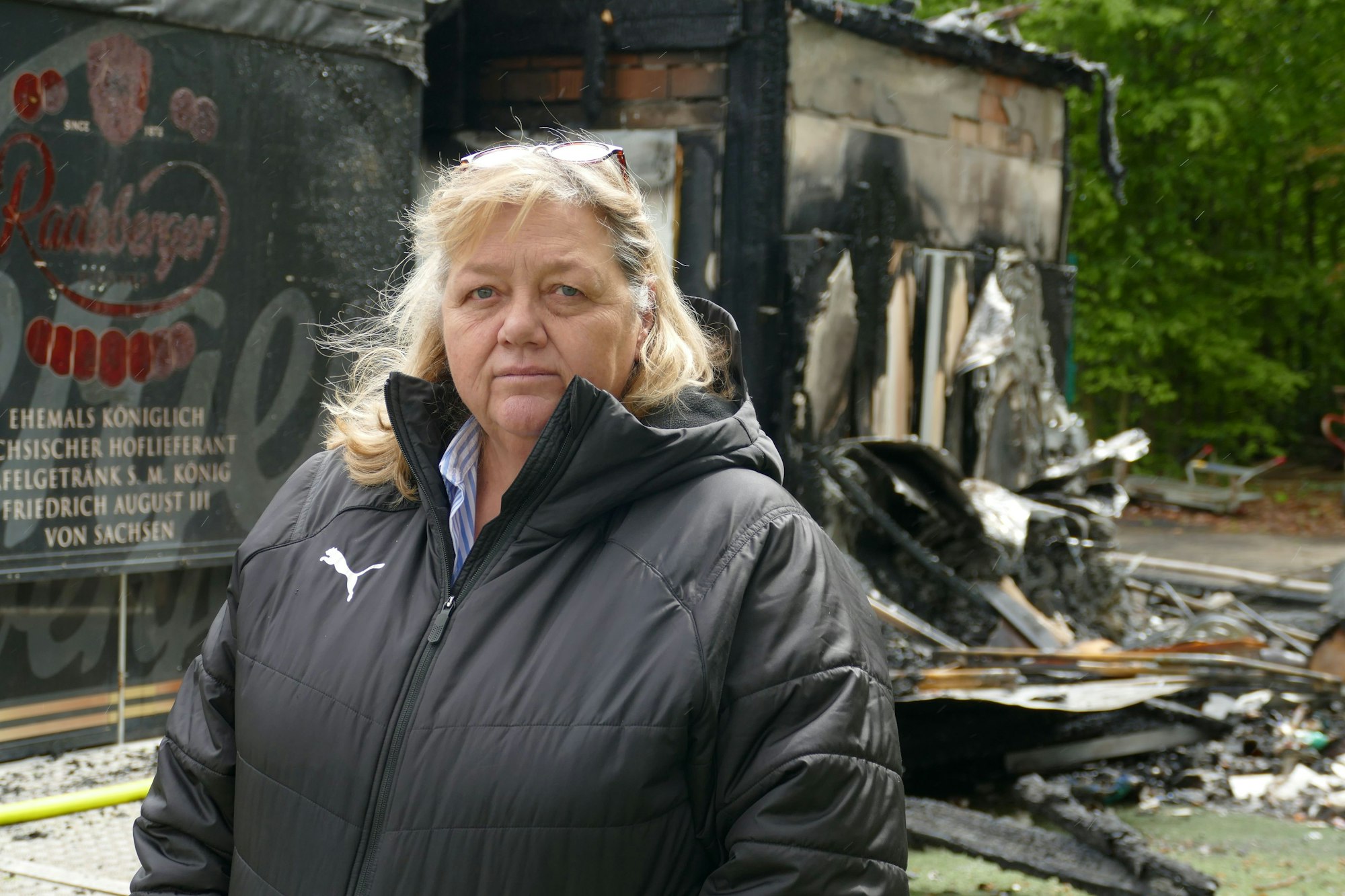 Eine Frau steht vor Brandschutt.