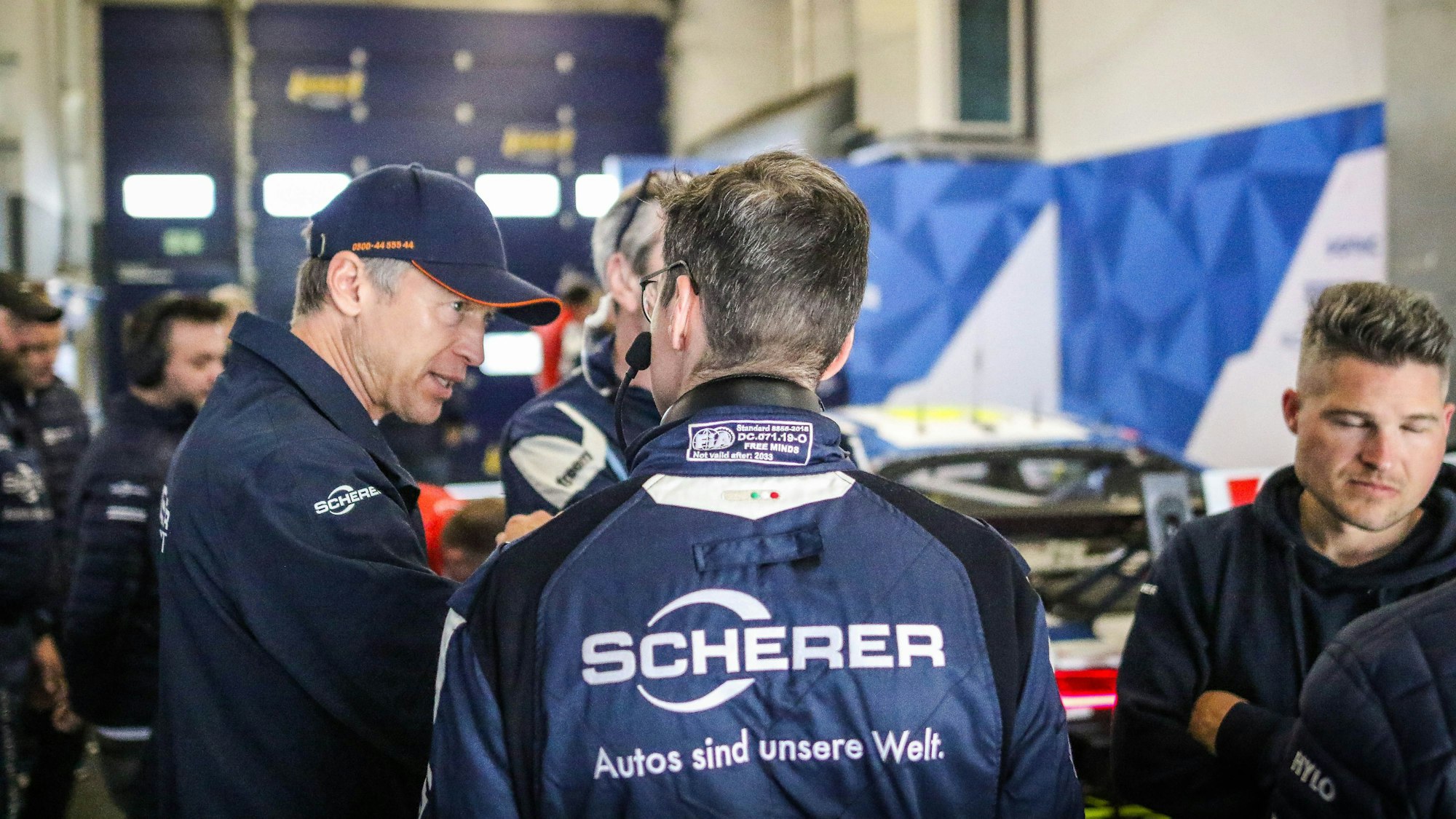 Frank Stippler mit blauer Kappe steht in der Box und bespricht sich mit seinem Team.