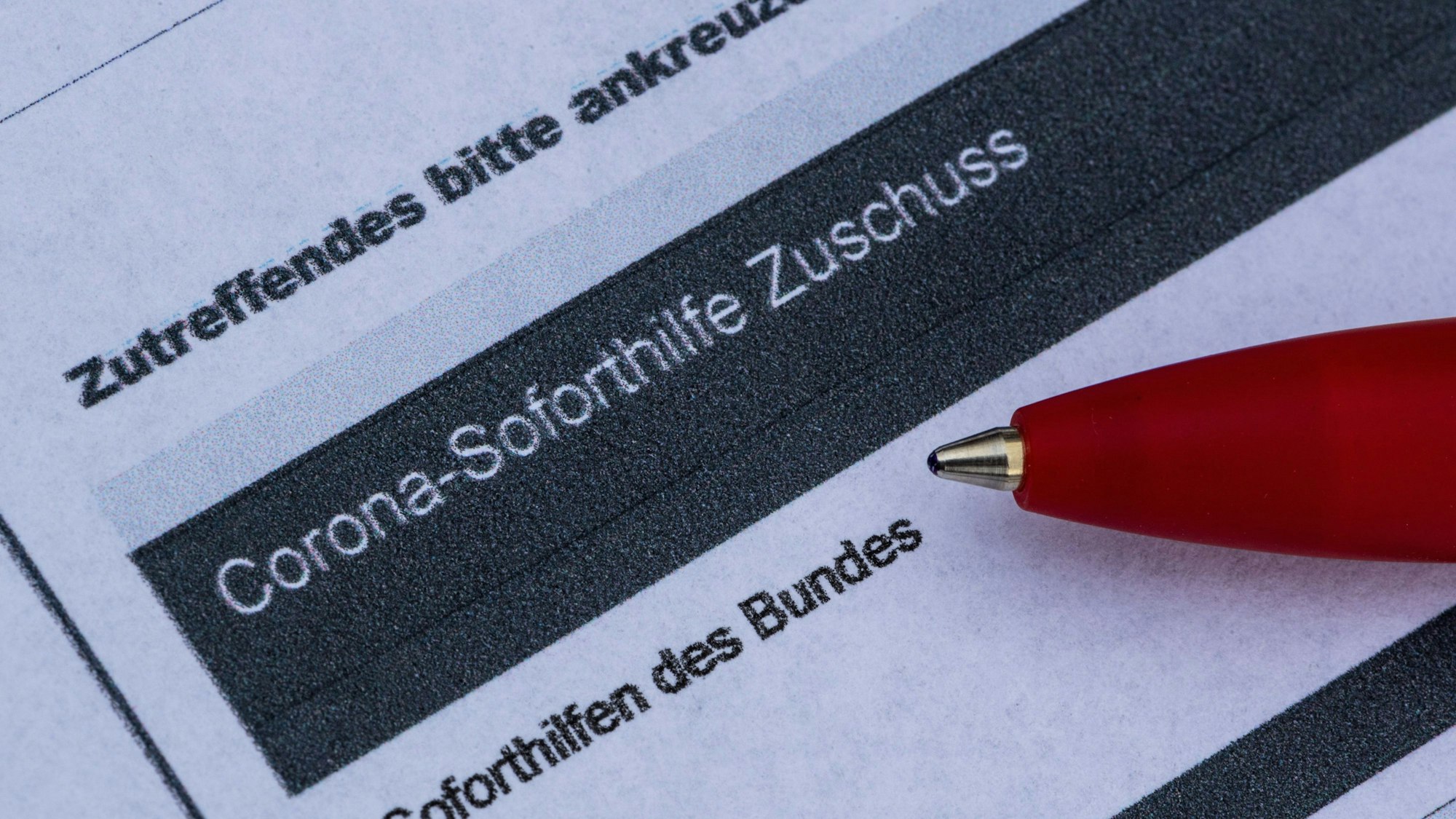 Ein Stift liegt auf einem Antrag für den Corona-Soforthilfe-Zuschuss.