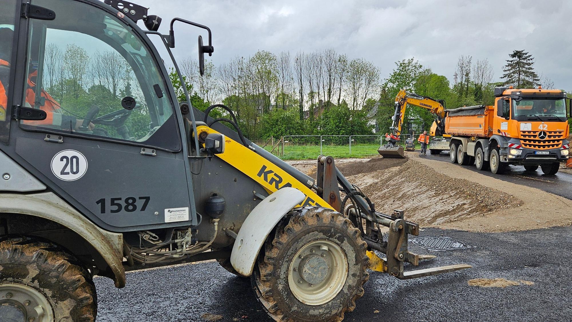 Ein Bagger und andere Baufahrzeuge stehen in einem Neubaugebiet.