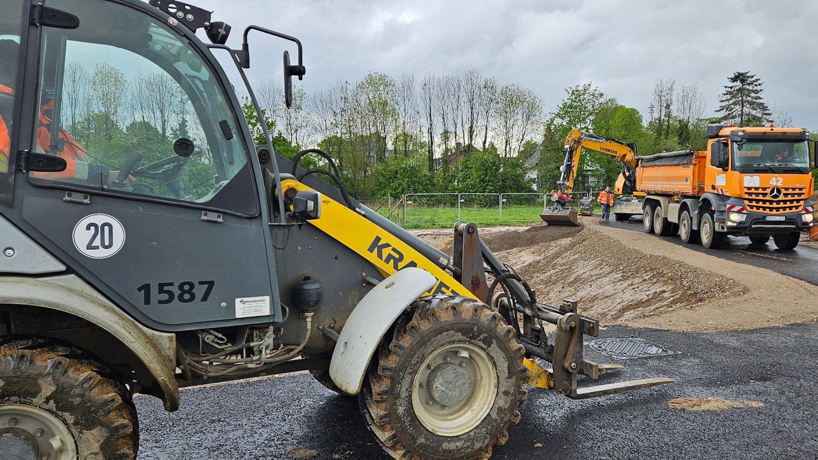 Ein Bagger und andere Baufahrzeuge stehen in einem Neubaugebiet.
