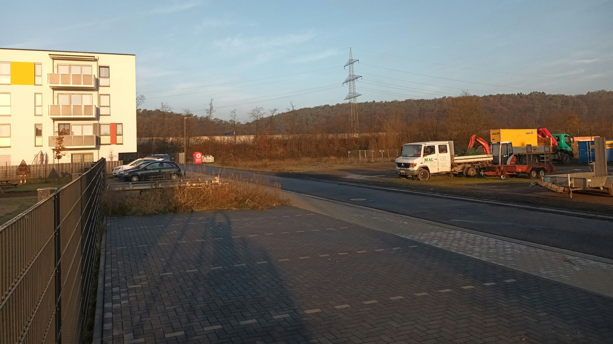 Ein Haus, eine Straße und eine Freifläche mit Baumaschinen