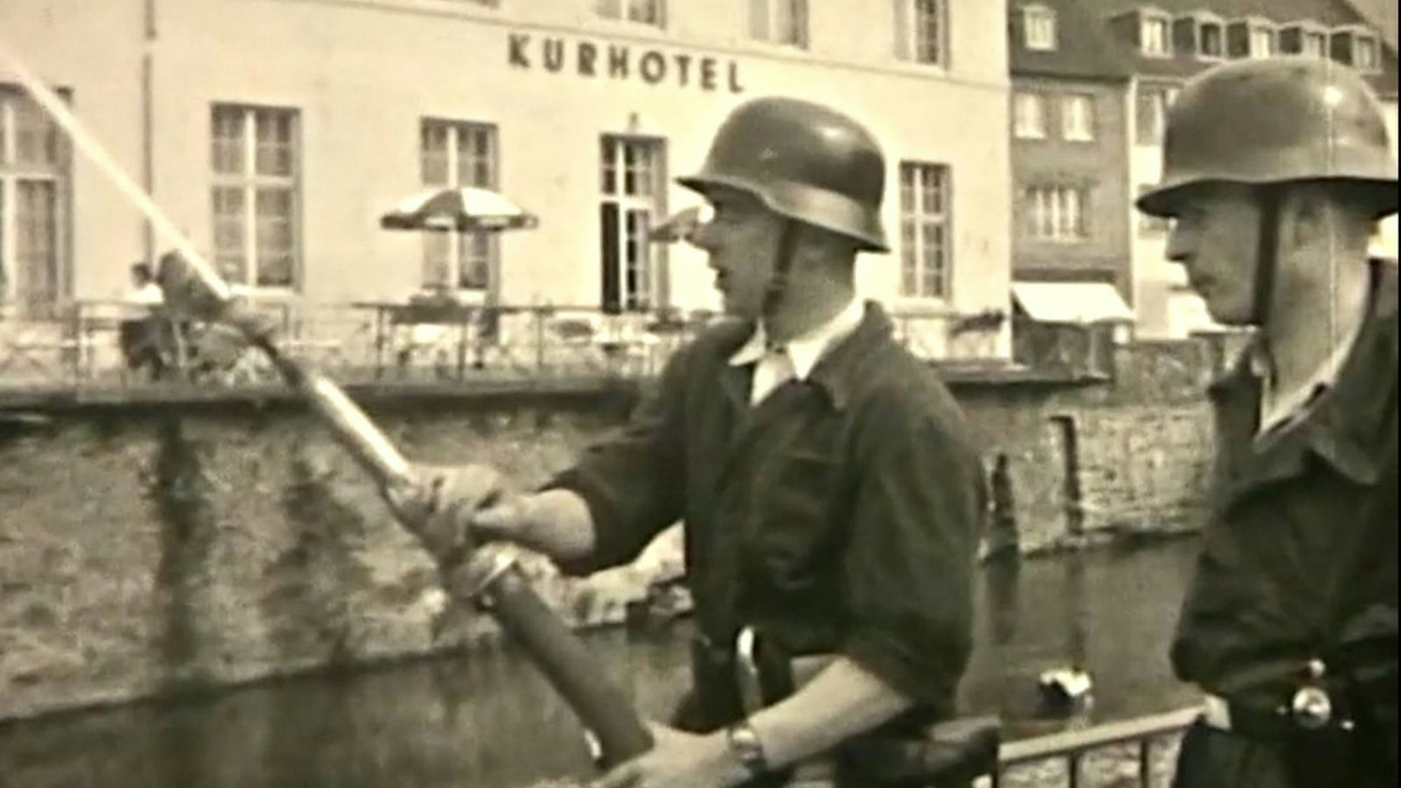 Zwei Feuerwehrleute stehen vor dem ehemaligen Kurhotel, einer hält einen Schlauch.