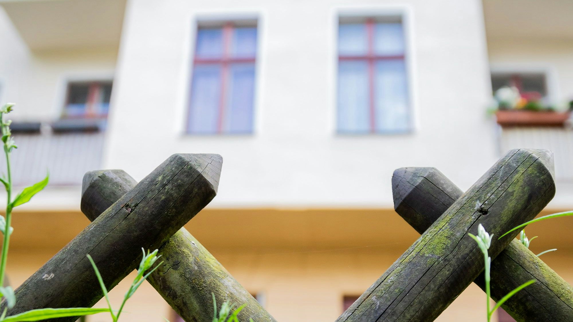 Ein Zaun vor einem Haus mit Garten