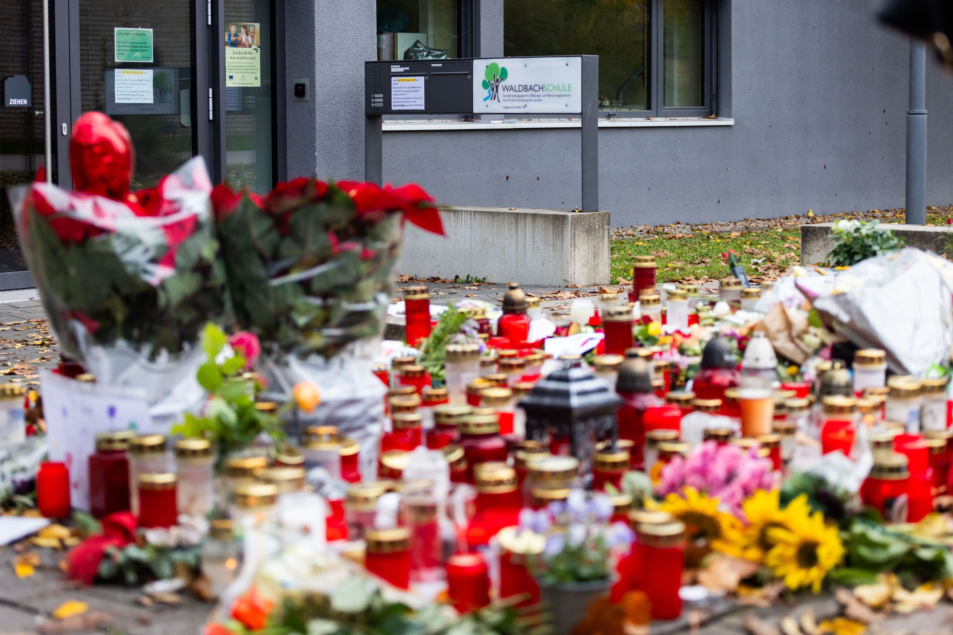 Kerzen und Blumen liegen vor dem Eingang der Waldbachschule.