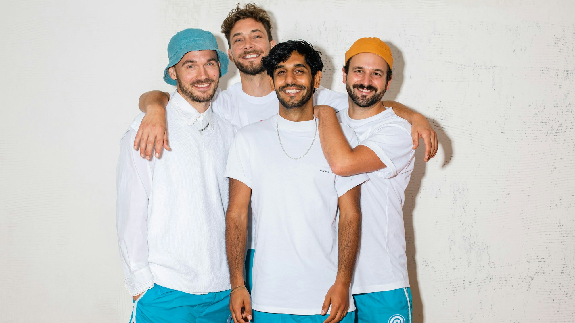 Die vier Bandmitglieder stehen zusammen und grinsen in die Kamera.