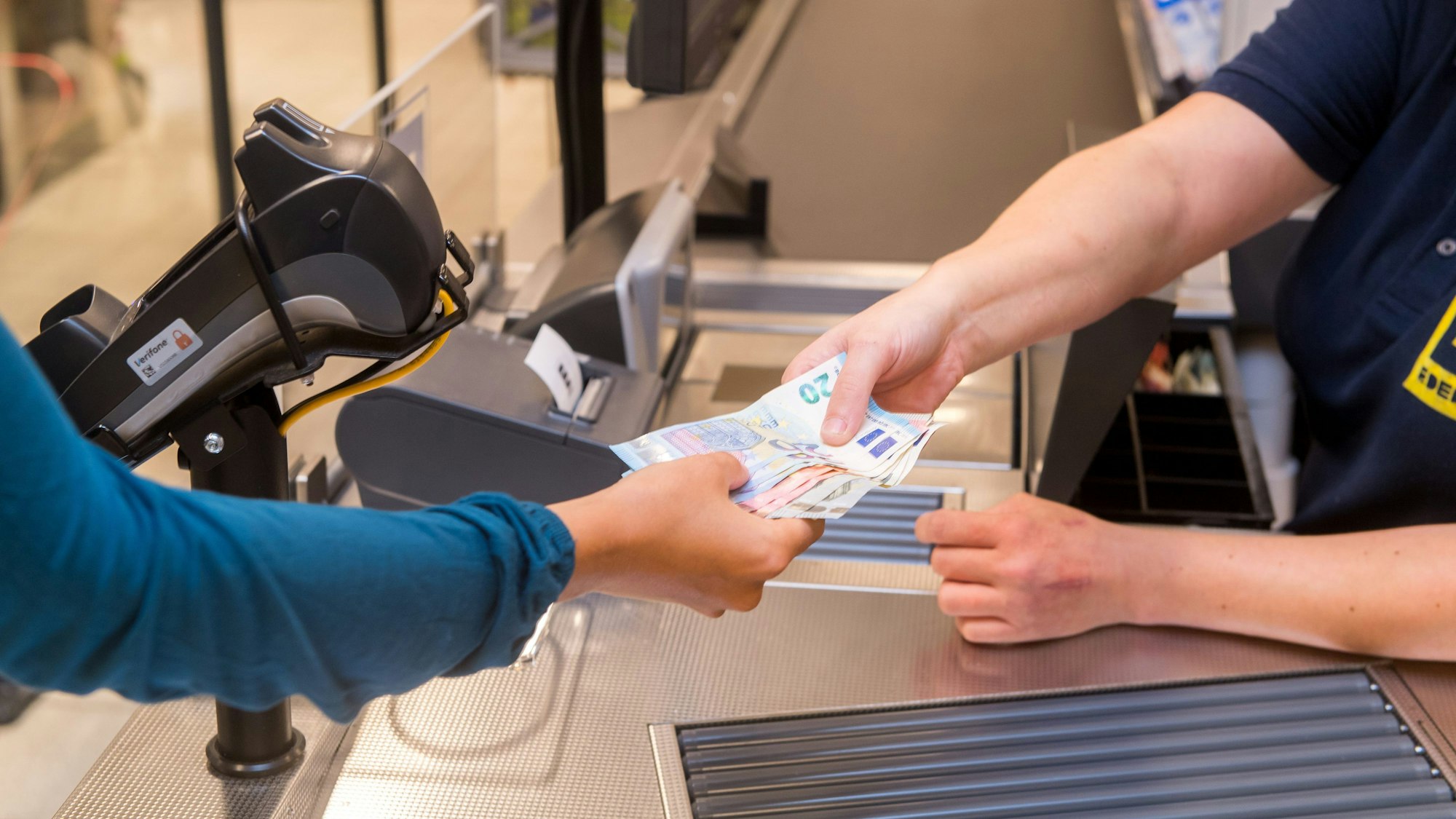 In einem Supermarkt hebt eine Kundin beim Bezahlen auch gleich Bargeld ab.