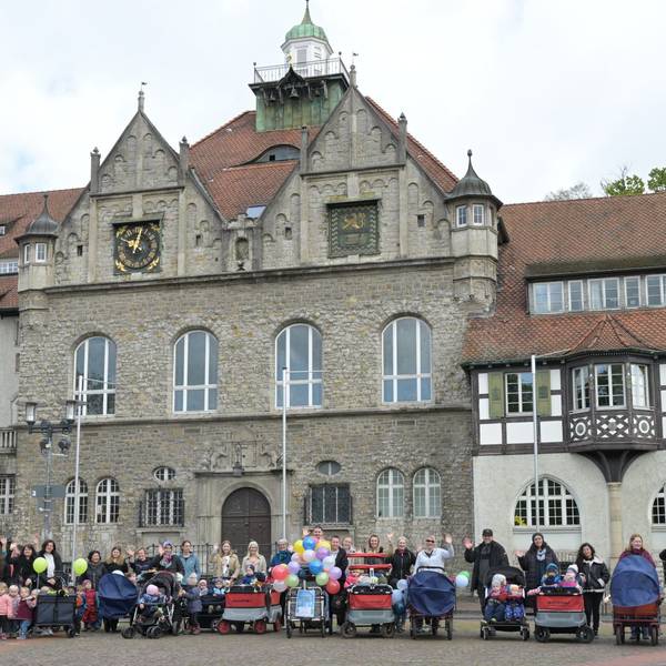 Tagesmütter mit Kinderwagen und Kindern an der Hand stehen vor dem Rathaus in Bergisch Gladbach.