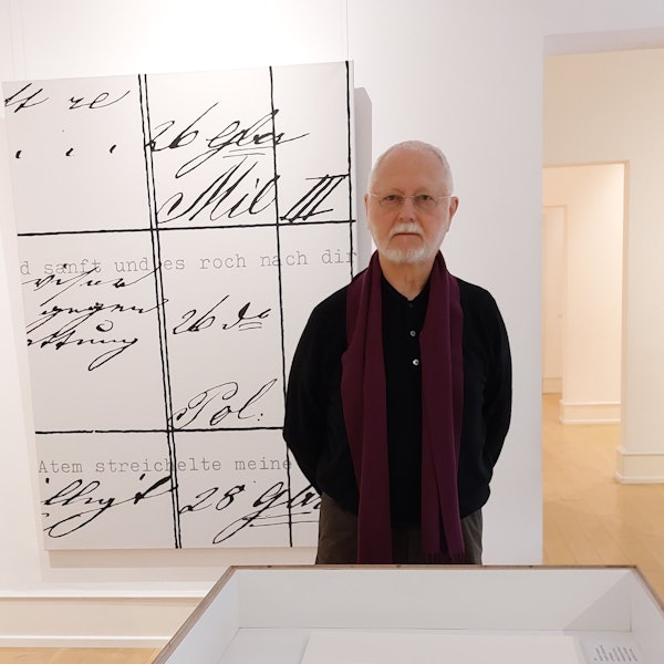 Ein älterer Herr steht vor einem großformatigen Gemälde; zu sehen sind Fragmente eines Gedichts in Schreibmaschinenschrift, außerdem Worte in einer alten Urkundenschrift.