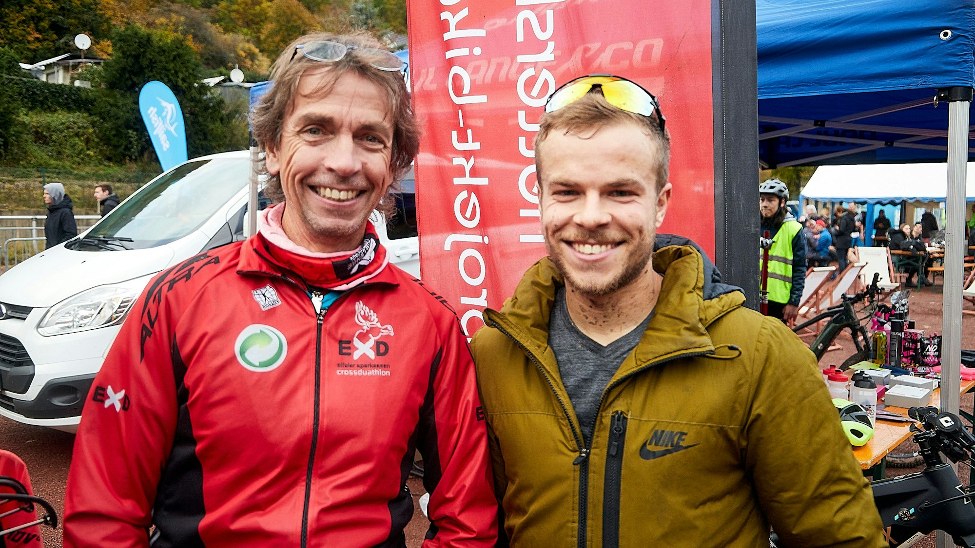 Der Crossduathlon-Organisator trägt eine rote Jacke mit EXD-Logo. Neben ihm steht sein Sohn.