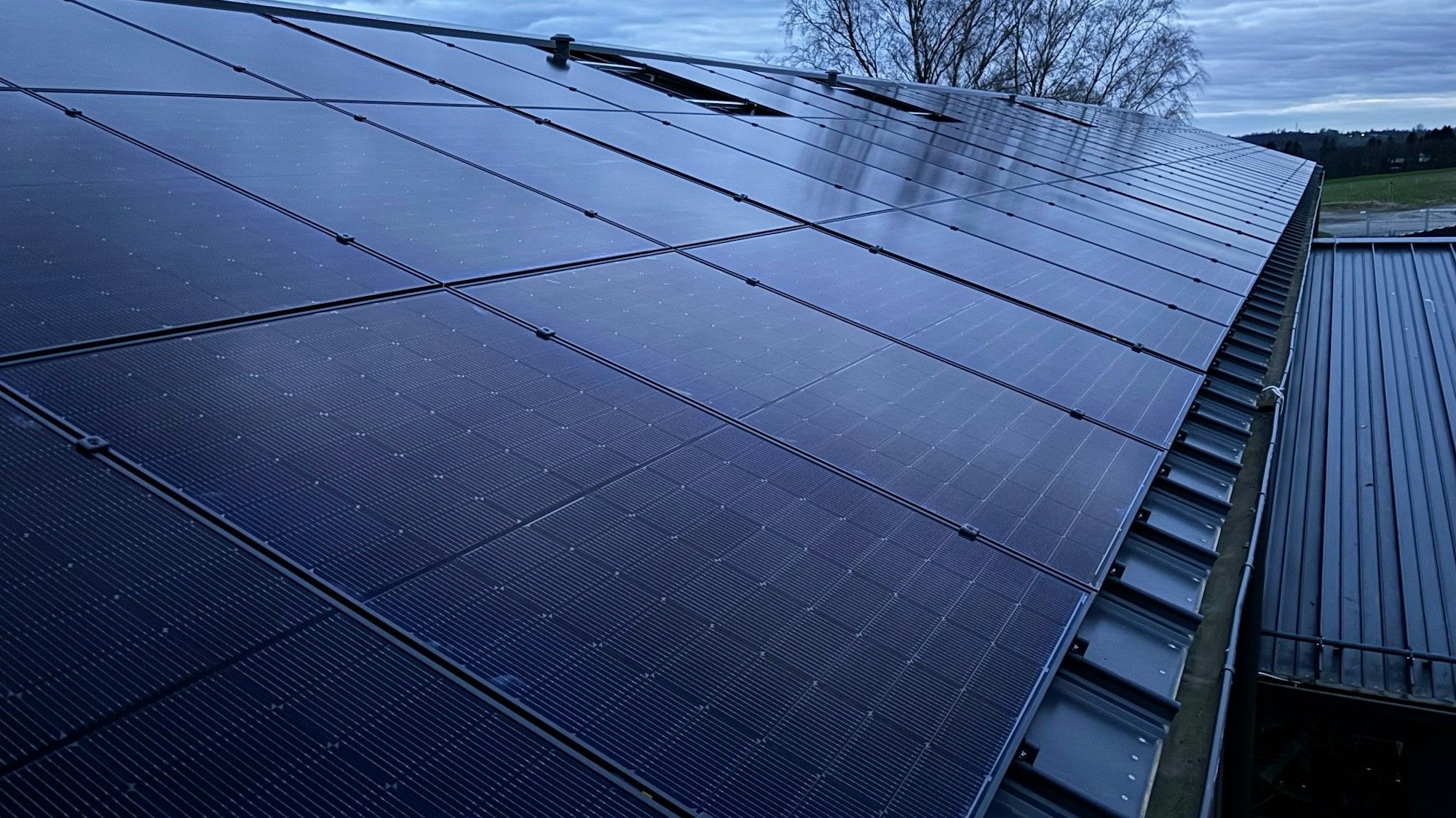 Zu sehen ist das Dach der Turnhalle, das mit Solarmodulen belegt ist.