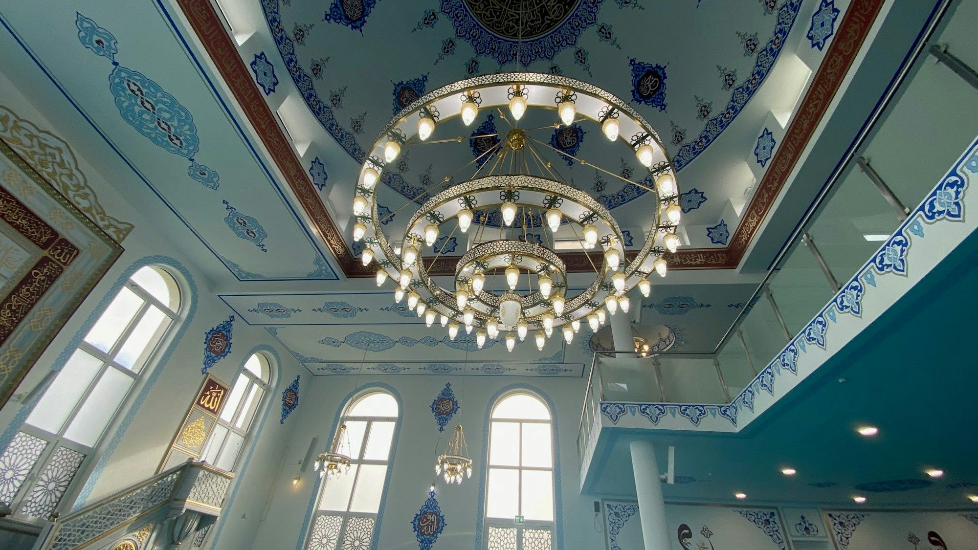 Zu sehen ist der Gebetsraum für Männer, den ein großer Leuchter schmückt.
