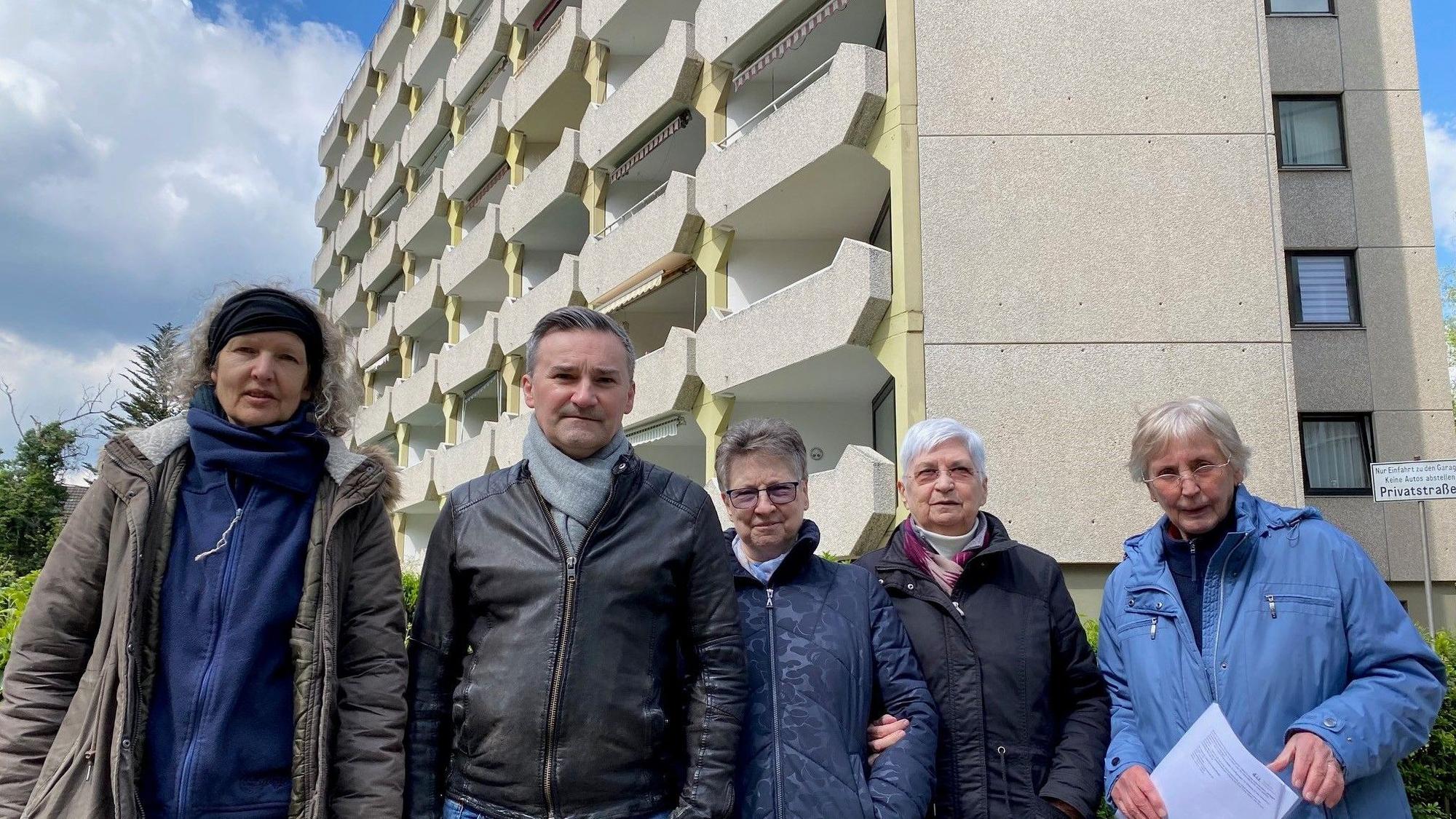 Zu sehen ist eine Gruppe von Menschen vor einem mehrgeschossigen Gebäude.