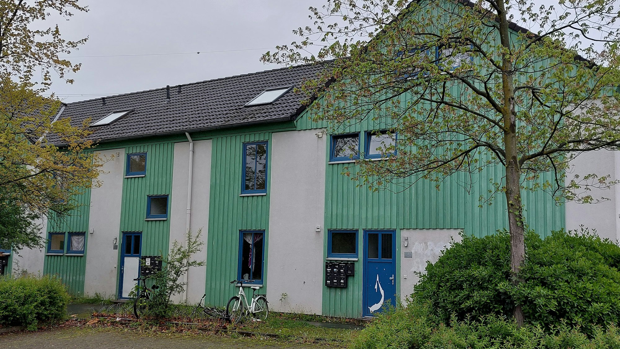 Reihenhäuser in grün und weiß; sie machen einen heruntergekommenen Eindruck.