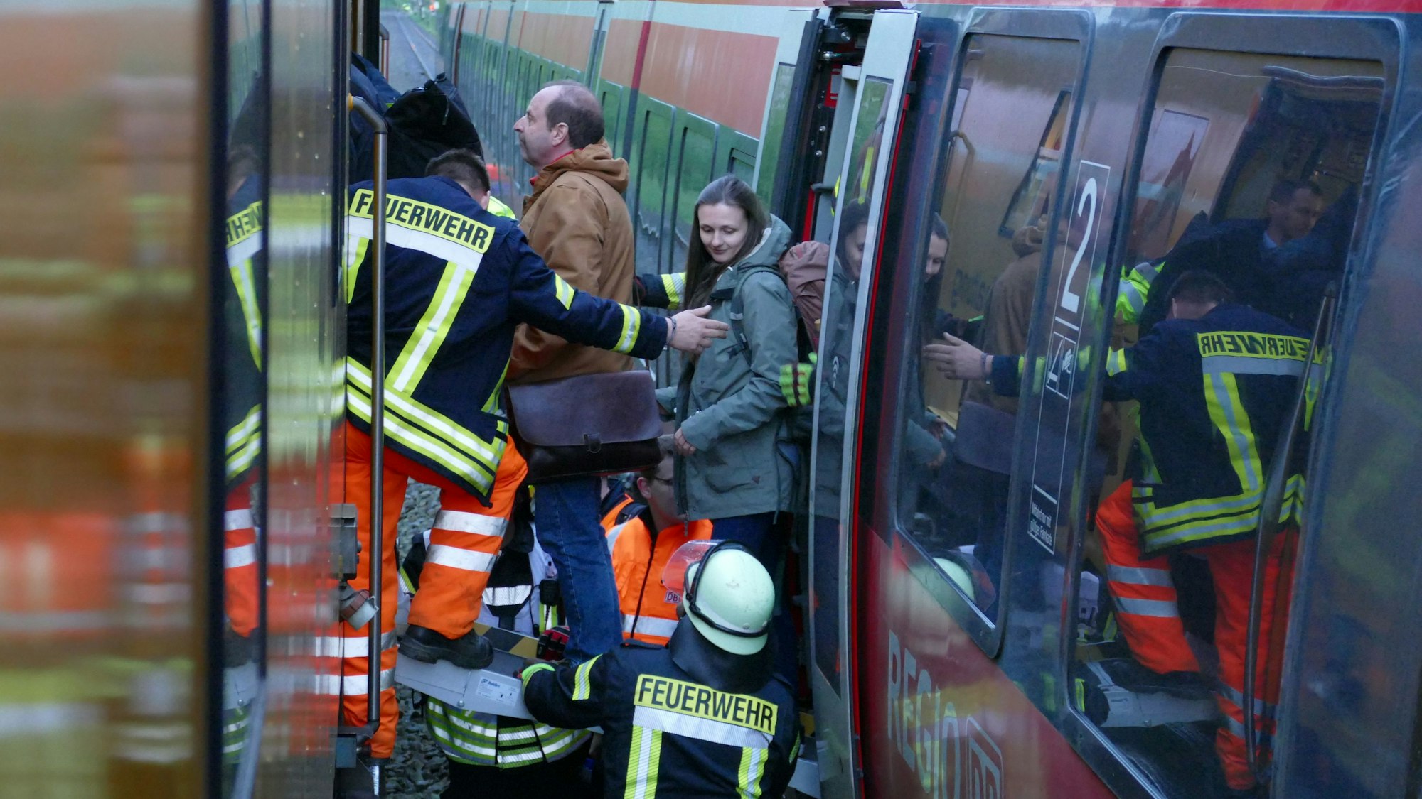 Passagiere eines Regionalzugs werden über eine Rollstuhlrampe in eine Instandhaltungslok geführt.