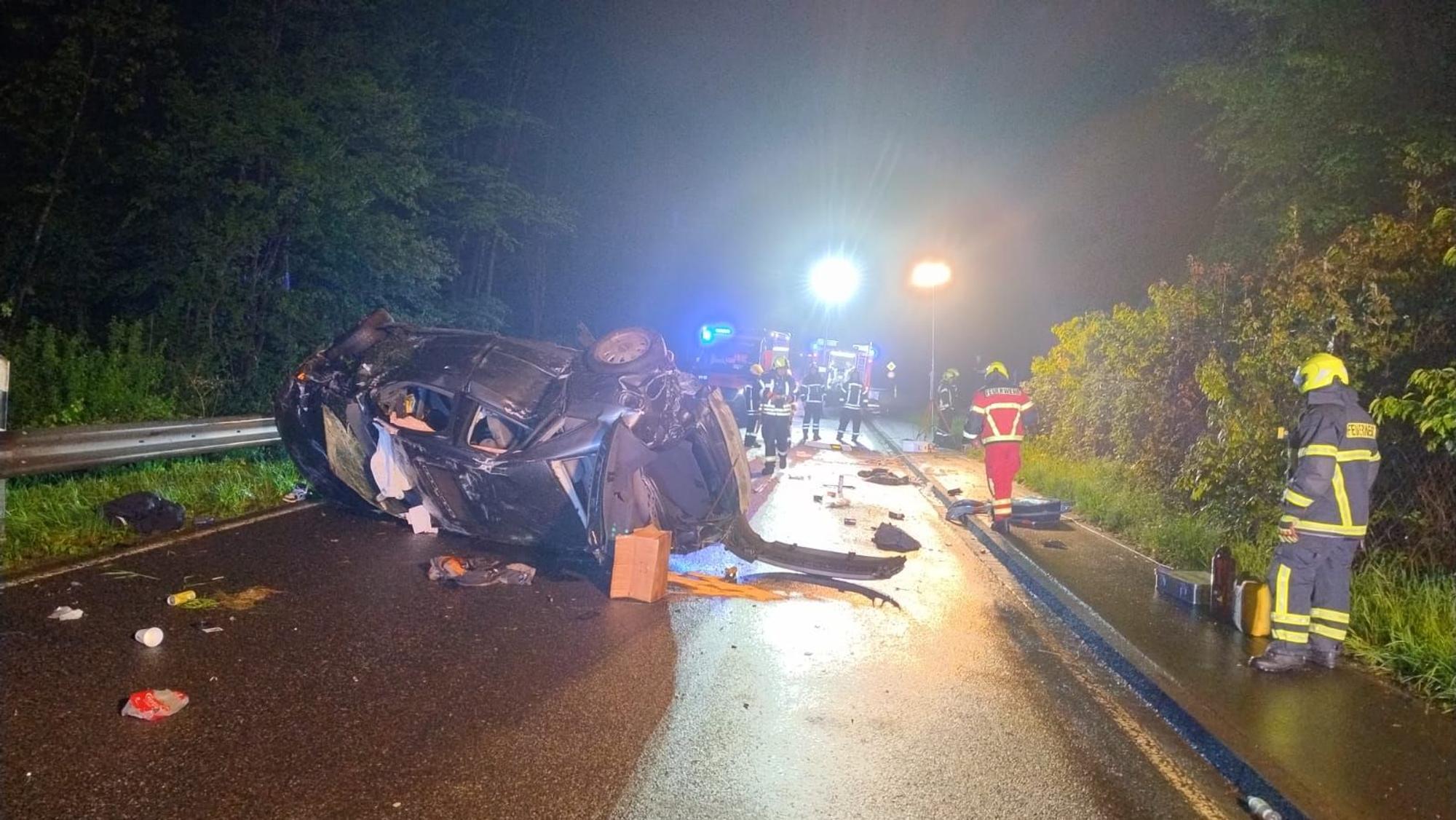 Rettungskräfte stehen um ein Autowrack herum.