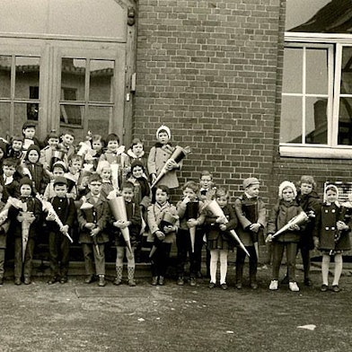 Ein Schwarzweißfoto zeigt Kinder mit Schultüten vor einem Schulgebäude. Das Foto ist vor 60 Jahren entstanden.