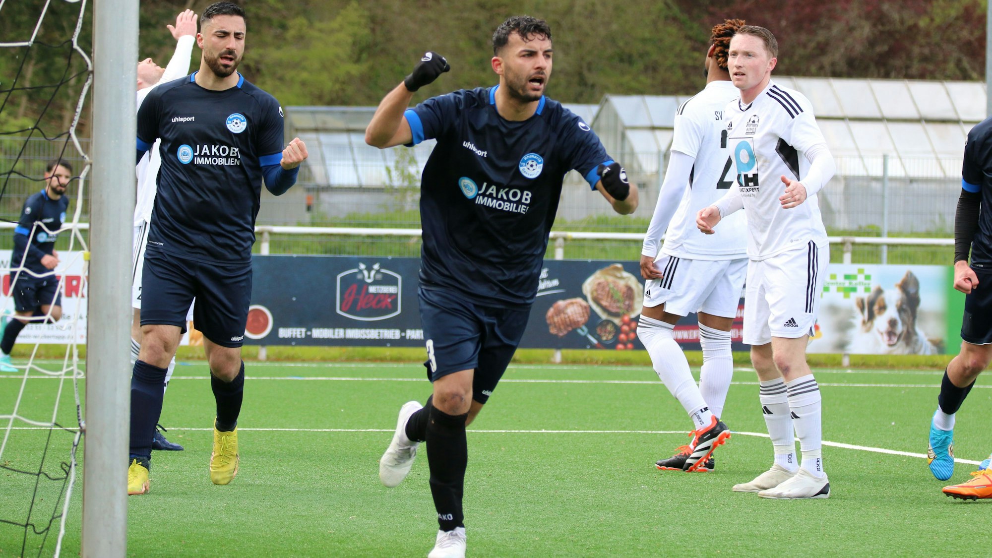 Ein Bessenicher Spieler streckt die Faust zum Jubeln in die Höhe. Ein Mitspieler tut es ihm gleich. Ein Nierfelder Spieler macht eine Verzweiflungsgeste.